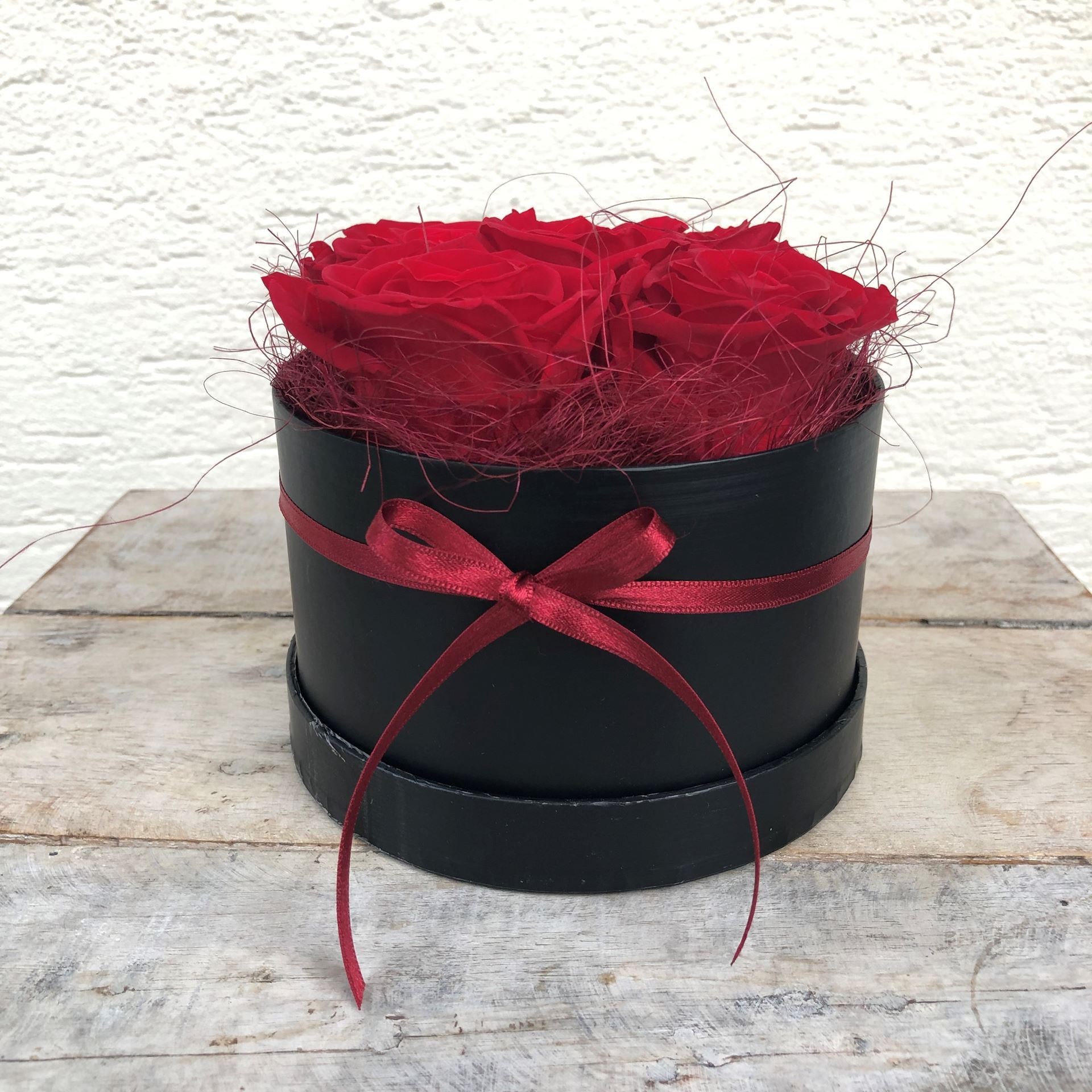 Eine edle Rosenbox - rund, in Schwarz, mit 5 roten, echten, stabilisierten Rosen  Ø ca. 13 cm