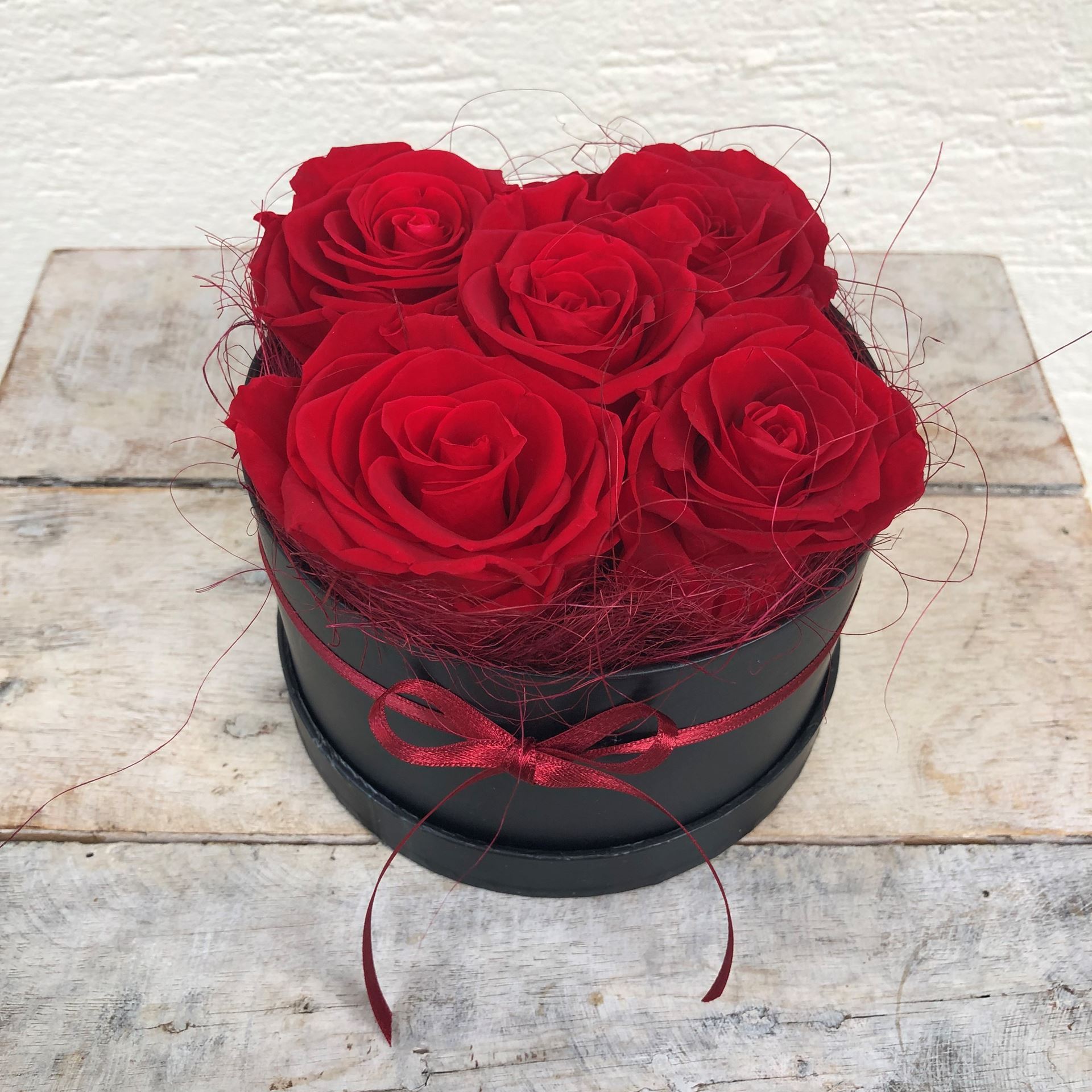 Eine edle Rosenbox - rund, in Schwarz, mit 5 roten, echten, stabilisierten Rosen  Ø ca. 13 cm