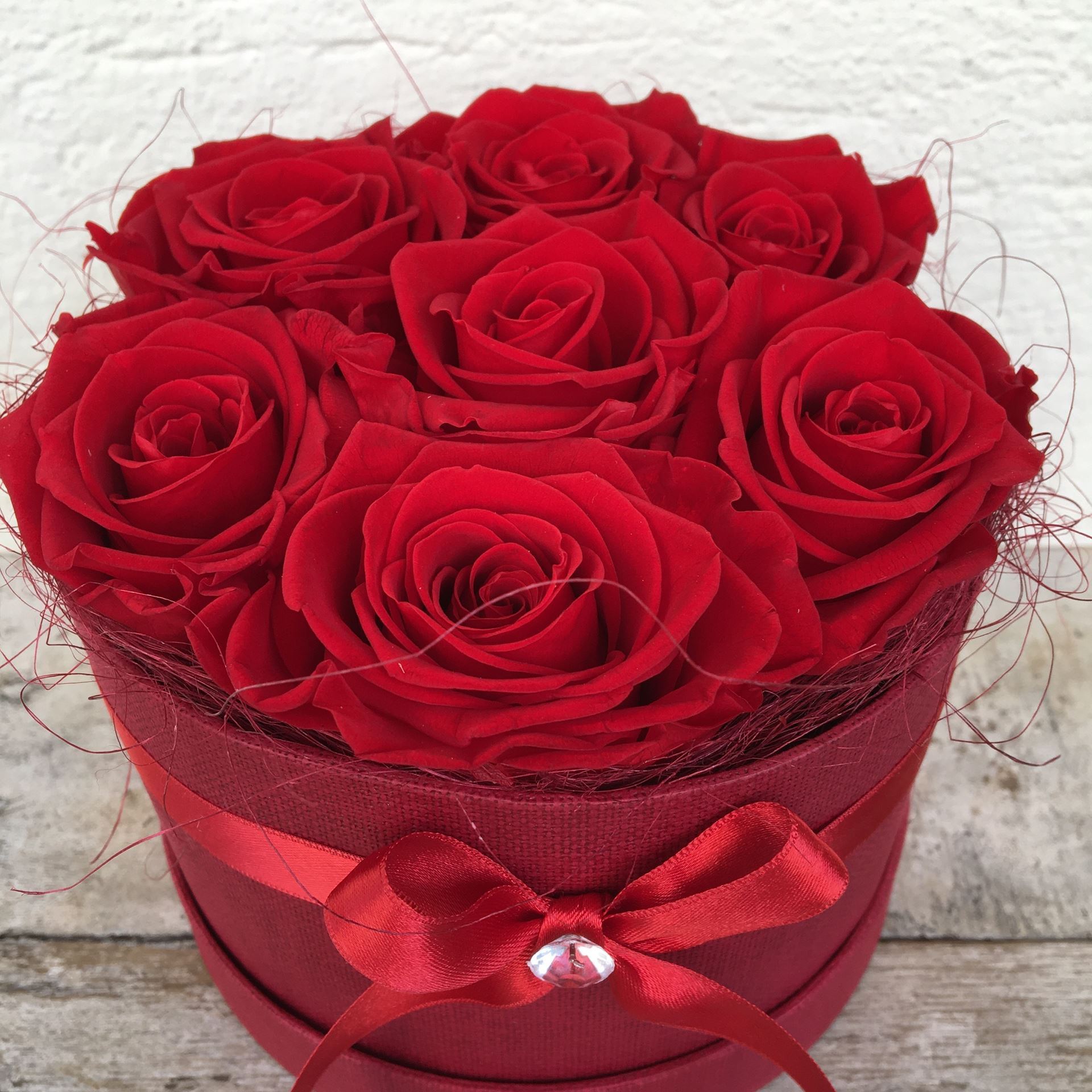 Eine edle Rosenbox - rund, in rot, mit 7 roten, echten, stabilisierten Rosen  Ø ca. 15 cm